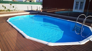 Une piscine rectangulaire avec une échelle sur un des côtés, entourée d’une terrasse en bois.