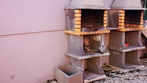 Deux fours en briques installés à l’extérieur, dotés d ’une hotte en métal, et adossés à un mur rose.