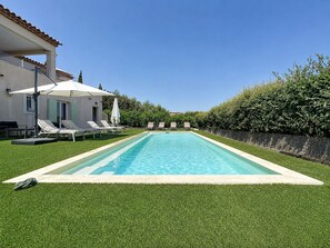 A rectangular swimming pool with a white edge, surrounded by a well-maintained lawn and a row of white lounge chairs. - Luxury 4-Bedroom Villa in Saint-Tropez with Panoramic Sea Views (Saint-Tropez)
