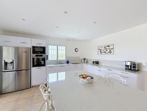 A modern kitchen with stainless steel appliances, a central island, and a coffee maker. - Luxury 4-Bedroom Villa in Saint-Tropez with Panoramic Sea Views (Saint-Tropez)