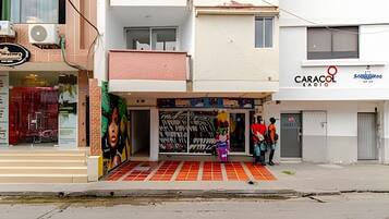 A street view with a building featuring a storefront with a colorful mural and a sign for 'CARACOL RADIO'.