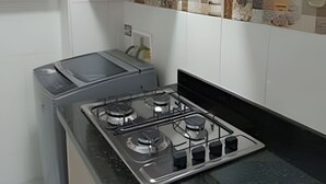 Una cocina con estufa a gas, armarios blancos y salpicadero de azulejos.