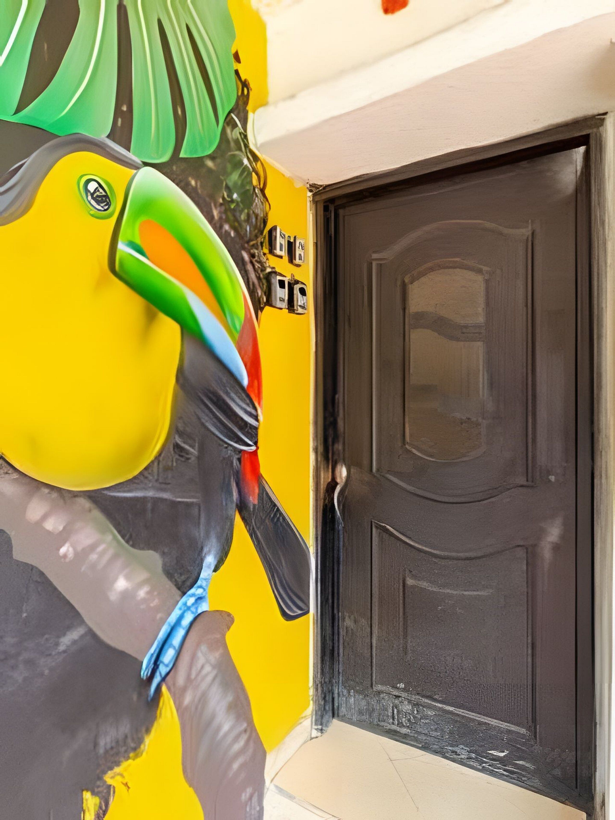 Una puerta con terminación oscura y una pared con un mural colorido.