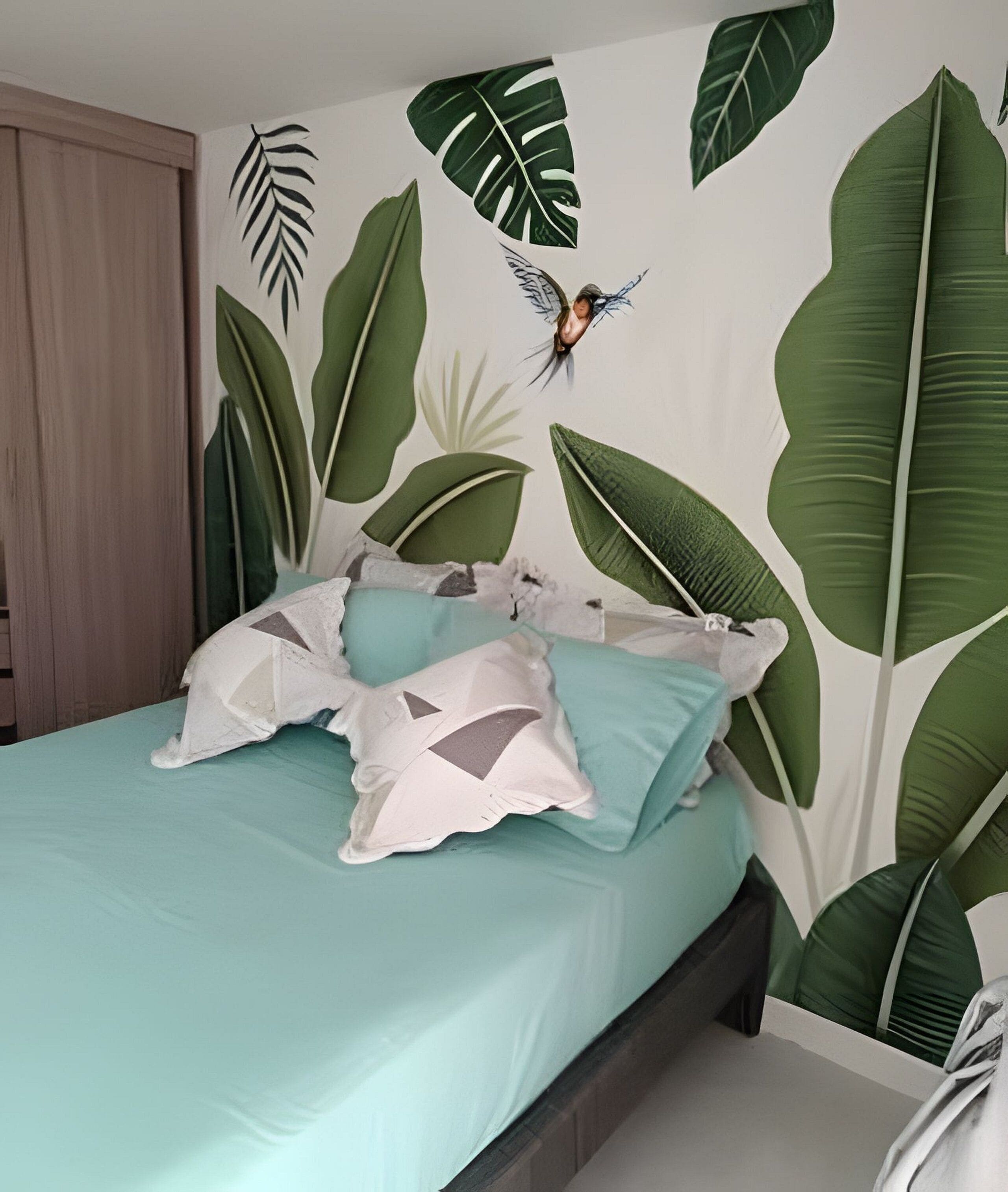A bedroom with a bed, pillows, and a wall with leaf patterns.