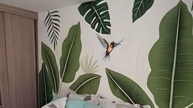 Un dormitorio con cama, almohadas y una pared decorada con motivos de hojas.