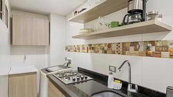 Eine moderne Küche mit einem Gasherd, einem Spülbecken und einer Kaffeemaschine auf einem Regal.
