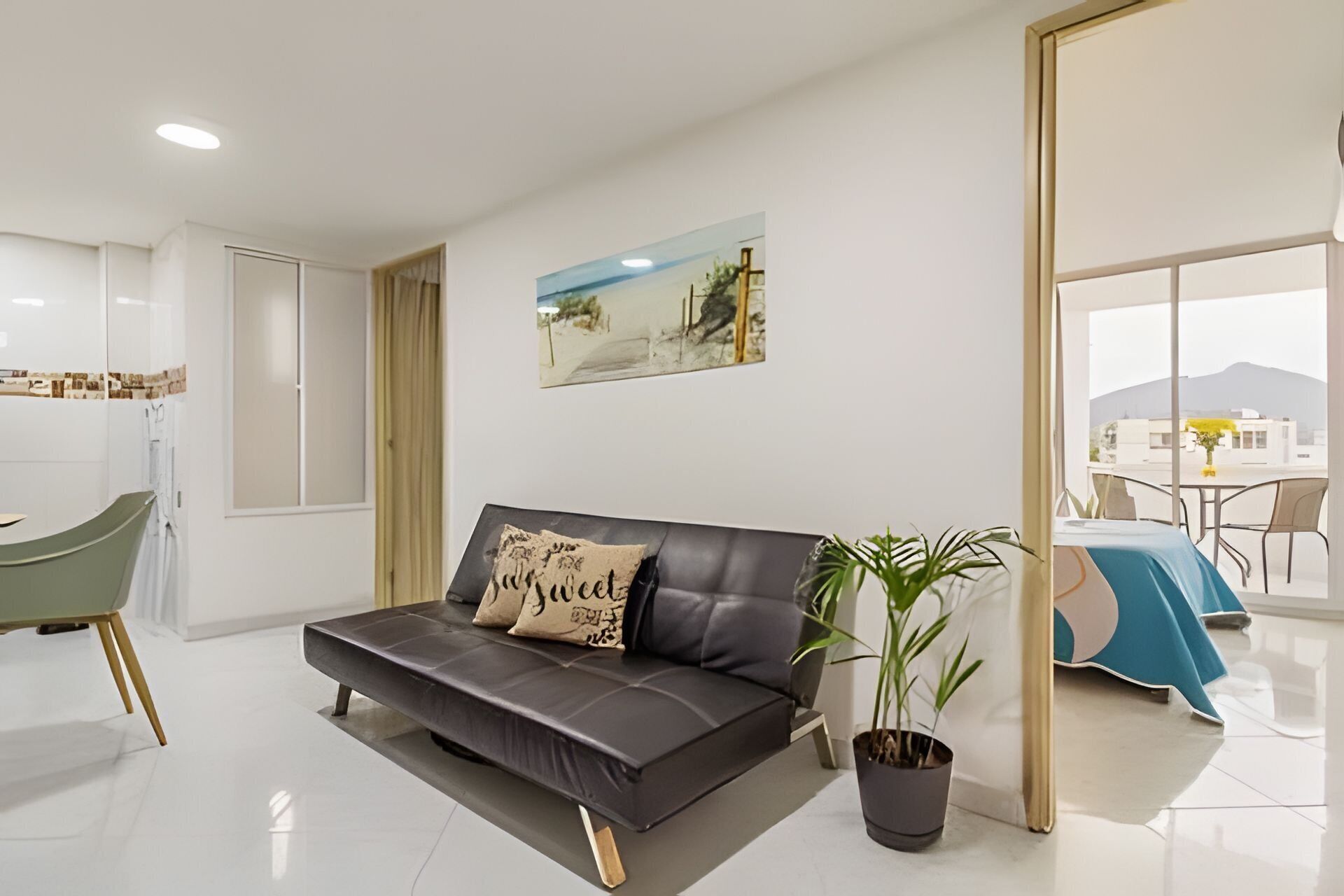 Ein modernes Wohnzimmer mit einer Ledersofa, einem Blumentopf und einem Essbereich mit Tisch und Stühlen.