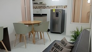 Un espacio habitable compacto con sofá, una mesa de comedor con sillas, una kitchenette y un refrigerador.