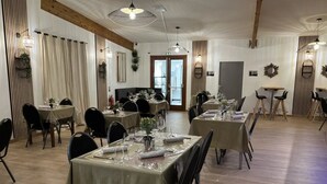 A dining area with tables set for service, wooden beams on the ceiling, and a view of the street through the door. - Chalet - Piscine  - ccbgdbd (Signy-le-Petit)