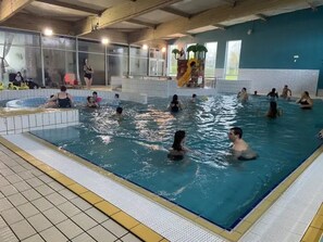 An indoor swimming pool with multiple lanes and a shallow area for children.