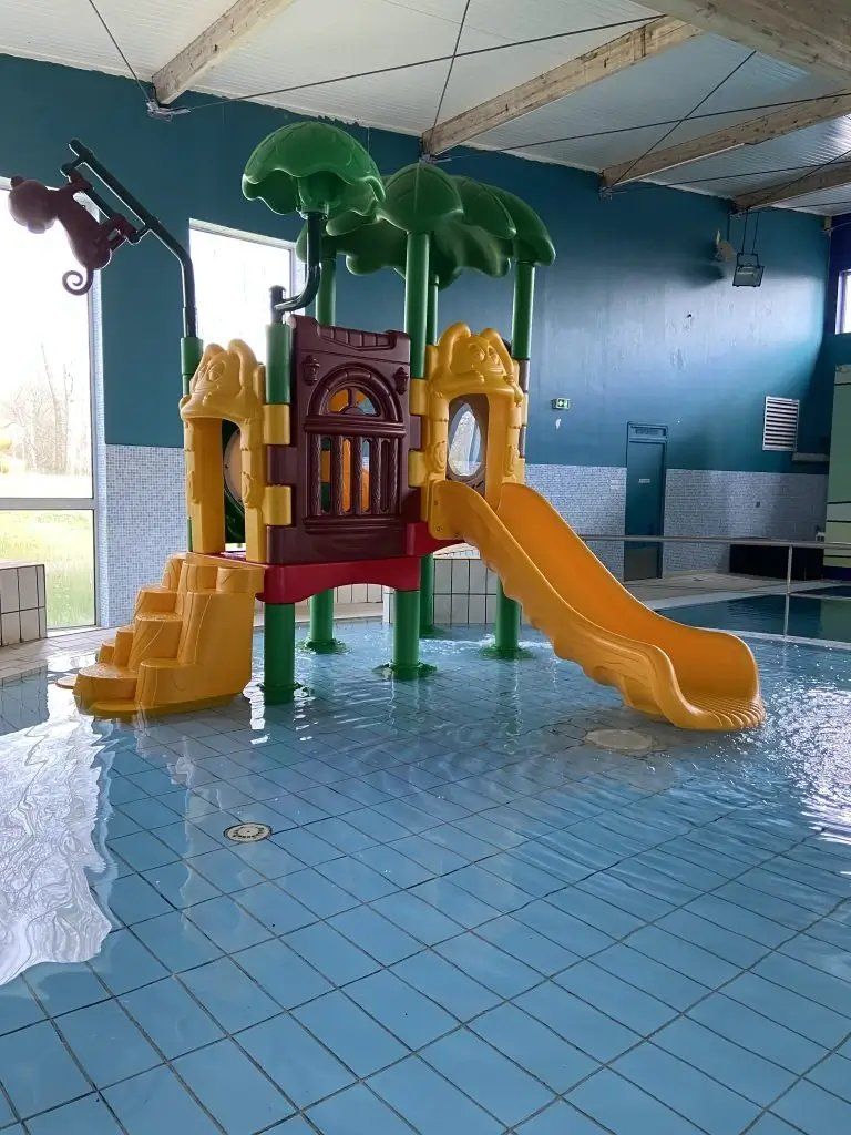 Een binnenspeelruimte met een glijbaan en klimconstructies.