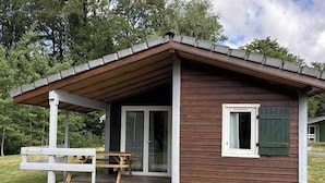 A small wooden cabin with a porch, a sliding glass door, and a bench. - Chalet 4 étoiles - Piscine  - ccbgdbf (Signy-le-Petit)