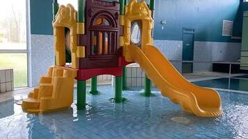 Un espace de jeux intérieur avec un toboggan et des structures d’escalade.