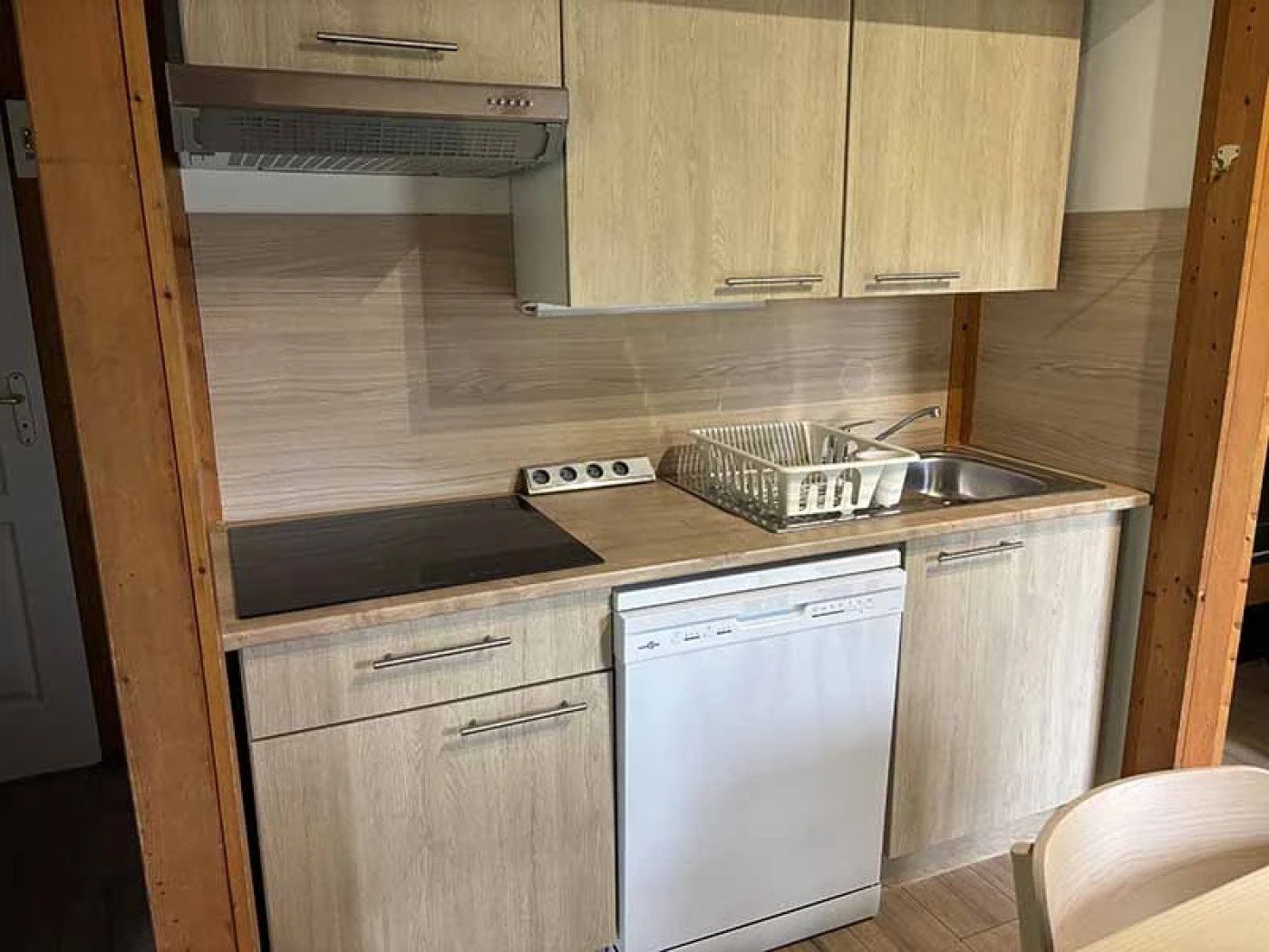 Een kleine keuken met houten kastjes, een vaatwasser en een spoelbak.