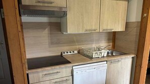 A compact kitchen with wooden cabinets, a dishwasher, and a sink. - Chalet 4 étoiles - Piscine  - ccbgdbf (Signy-le-Petit)