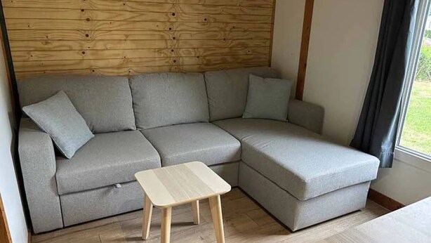 A modern living room with a grey sectional sofa, a small wooden coffee table, and a wooden headboard. - Chalet 4 étoiles - Piscine  - ccbgdbf (Signy-le-Petit)