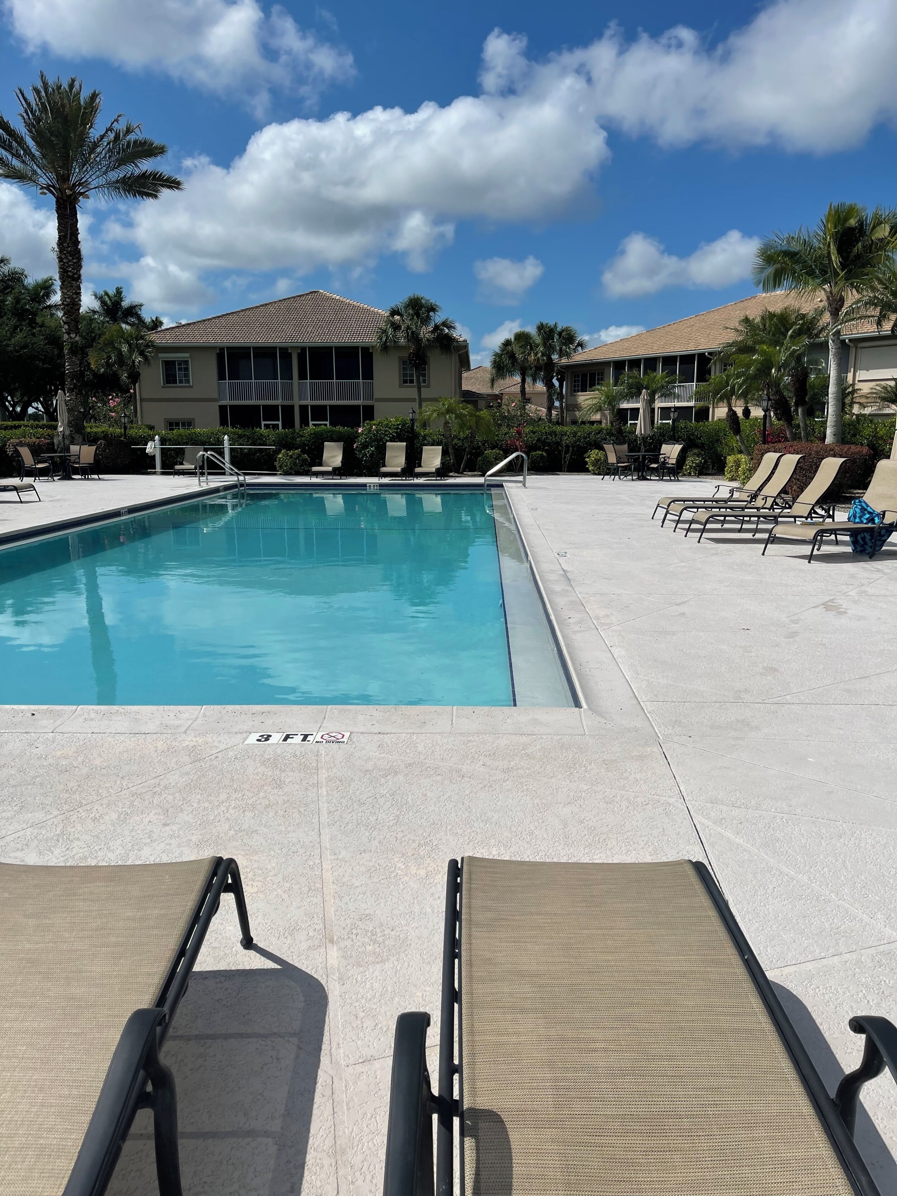 A swimming pool with lounge chairs and a building in the background.