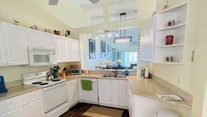 A kitchen with white cabinets, a microwave, stove, and a ceiling fan. - Spacious 3 bed, 2 bth condo,  great space, in unit laundry and one car garage (Naples)