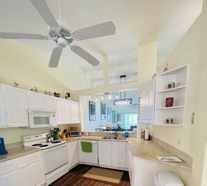 A kitchen with white cabinets, a microwave, stove, and a ceiling fan. - Spacious 3 bed, 2 bth condo,  great space, in unit laundry and one car garage (Naples)