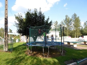 A playground with a netted climbing structure, a trampoline, and a picnic table. - Chalet 3 étoiles - Piscine  - ccbge0c (La Chapelle-devant-Bruyères)