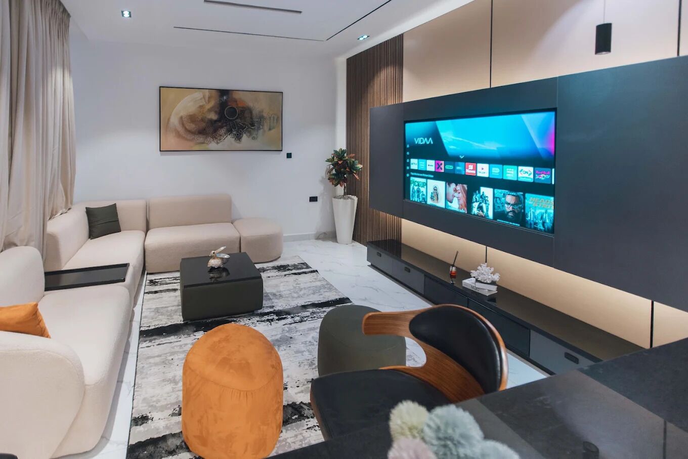 Un soggiorno moderno con un'ampia televisione a schermo piatto, un divano, un tavolino da caffè e un tappeto decorativo.