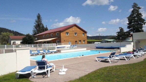 Ein Poolbereich mit Liegestühlen und einem Gebäude im Hintergrund.