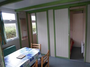 Ein Zimmer mit Tisch und Stühlen, einem Fenster und einer Tür zu einem anderen Raum.