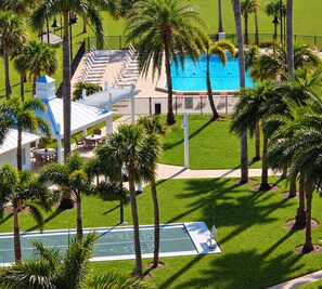 A pool area with lounge chairs and a tennis court. - Premium Luxury Top-Floor Bayside Penthouse (Fort Myers)