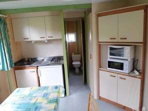 A compact kitchenette with a stove, microwave, and cabinets. - Chalet 3 étoiles - Piscine  - ccbgea0 (La Chapelle-devant-Bruyères)