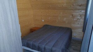 Ein Einzelbett in einem Zimmer mit Holzwänden und einem kleinen Nachttisch.