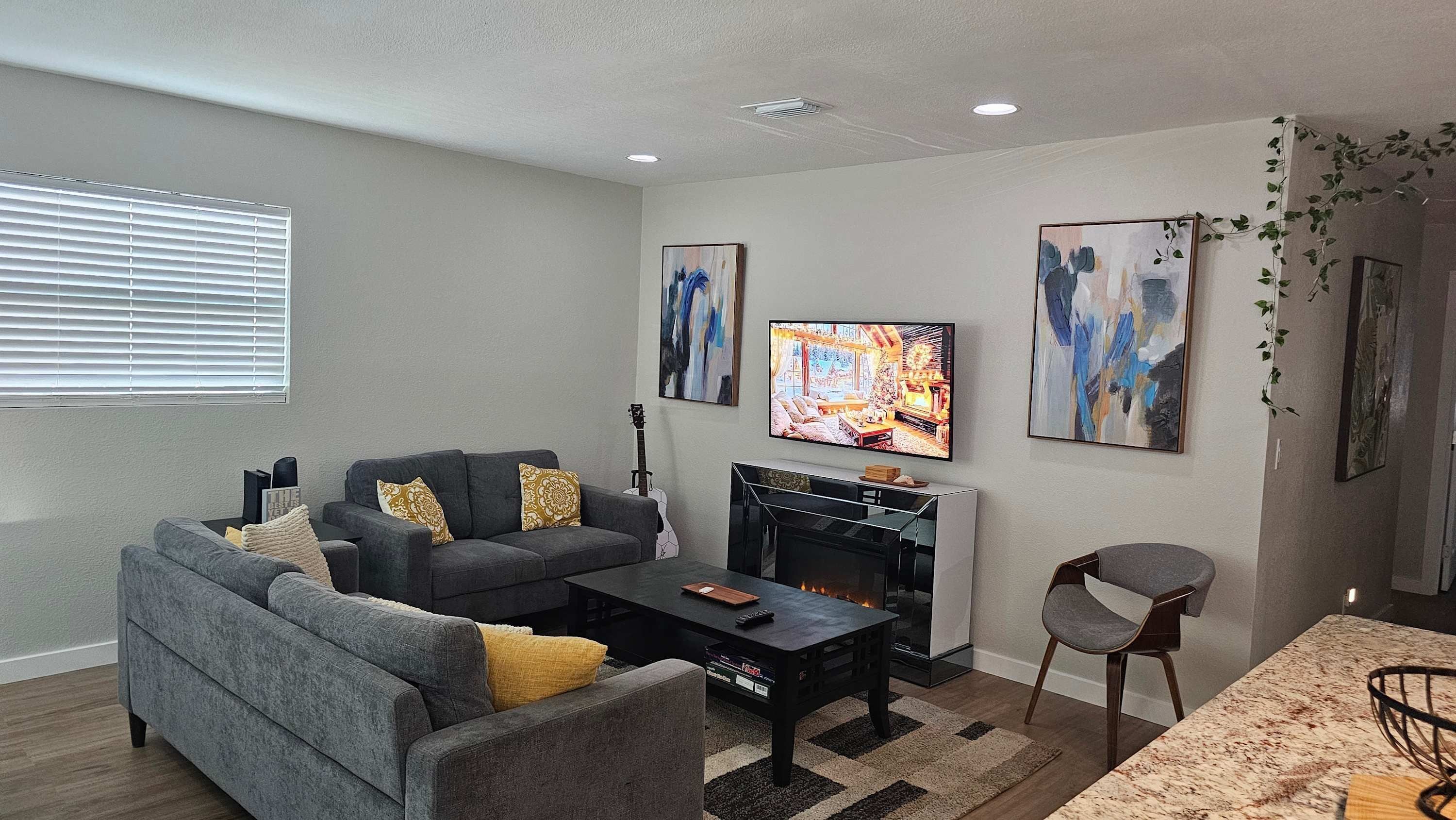 A living room with a sofa, coffee table, TV, fireplace, and artwork.