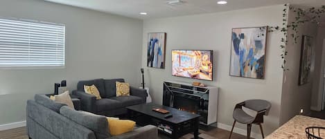 A living room with a sofa, coffee table, TV, fireplace, and artwork.