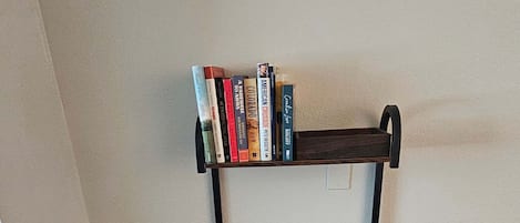 Un banc en bois avec une étagère au-dessus, adossé à un mur uni.