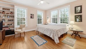 A bedroom with a bed, a chair, a desk, a bookshelf, and a ceiling fan. - Classic 5BR Davidson Retreat Walk Downtown Pet-friendly (Davidson)