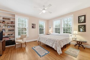 A bedroom with a bed, a chair, a desk, a bookshelf, and a ceiling fan. - Classic 5BR Davidson Retreat Walk Downtown Pet-friendly (Davidson)