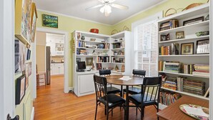 A room with a dining table, chairs, a ceiling fan, and bookshelves filled with books and decorative items. - Classic 5BR Davidson Retreat Walk Downtown Pet-friendly (Davidson)