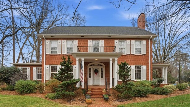 A two-story brick house with a front porch, a chimney, and a well-maintained lawn. - Classic 5BR Davidson Retreat Walk Downtown Pet-friendly (Davidson)