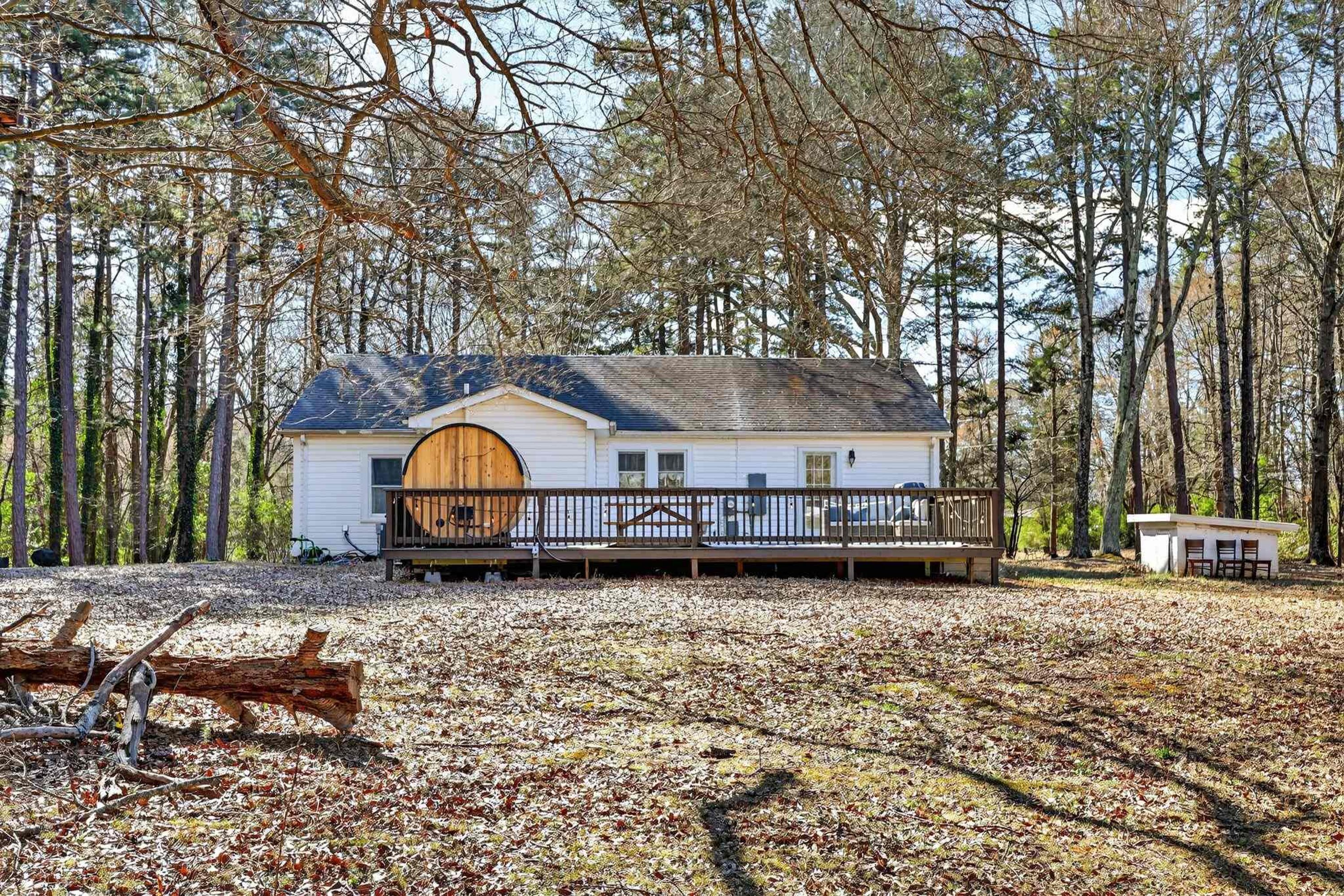 A cabin with a wooden deck, surrounded by a forest.