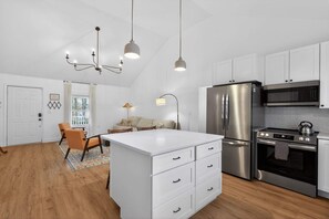 A modern kitchen with white cabinetry, stainless steel appliances, and a central island with drawers. - Cozy 3BR Cottage Sauna Minutes to Davidson (Mooresville)