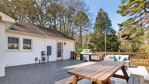 A wooden deck with a picnic table, a grill, and a white building with windows and a door. - Cozy 3BR Cottage Sauna Minutes to Davidson (Mooresville)