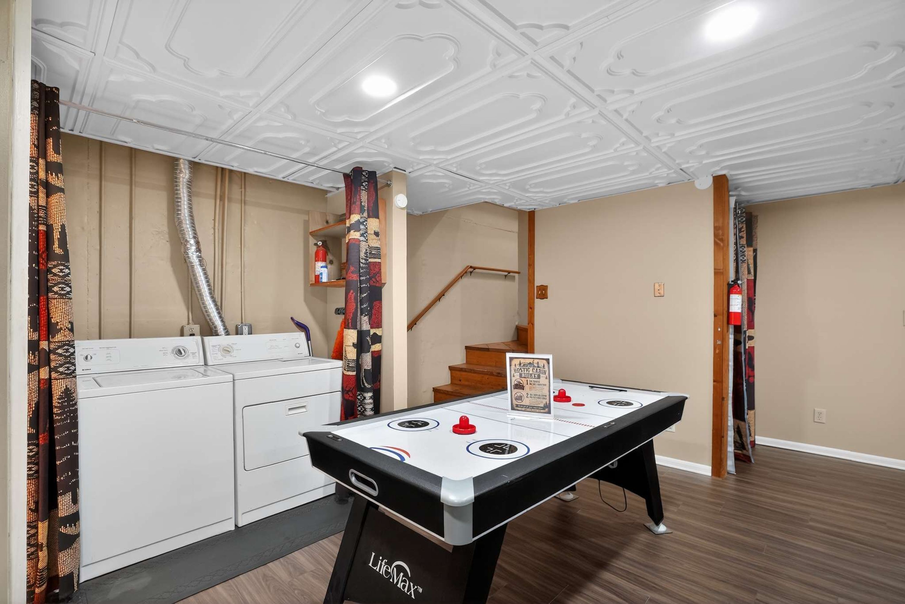 A room with a pool table, a washing machine, and a staircase.