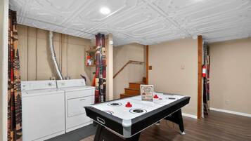 A room with a pool table, a washing machine, and a staircase.