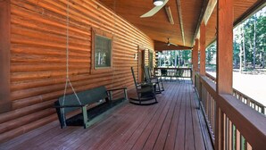 A wooden cabin with a porch, a swing, and a ceiling fan. - Cabin Outdoor Space Views Gym Game Room (Ellenwood)