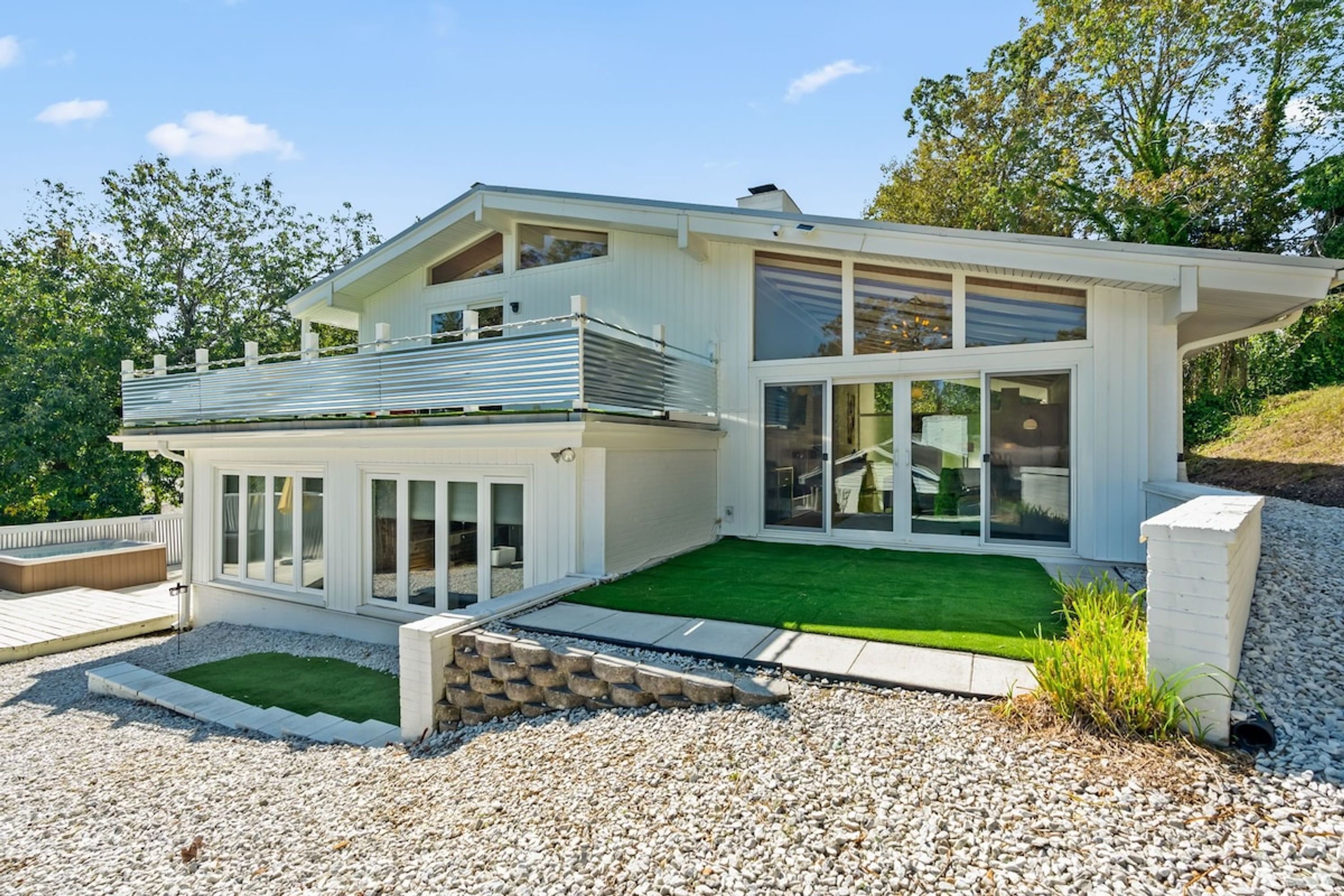 A modern two-story house with a covered patio, a swimming pool, and a well-maintained lawn.