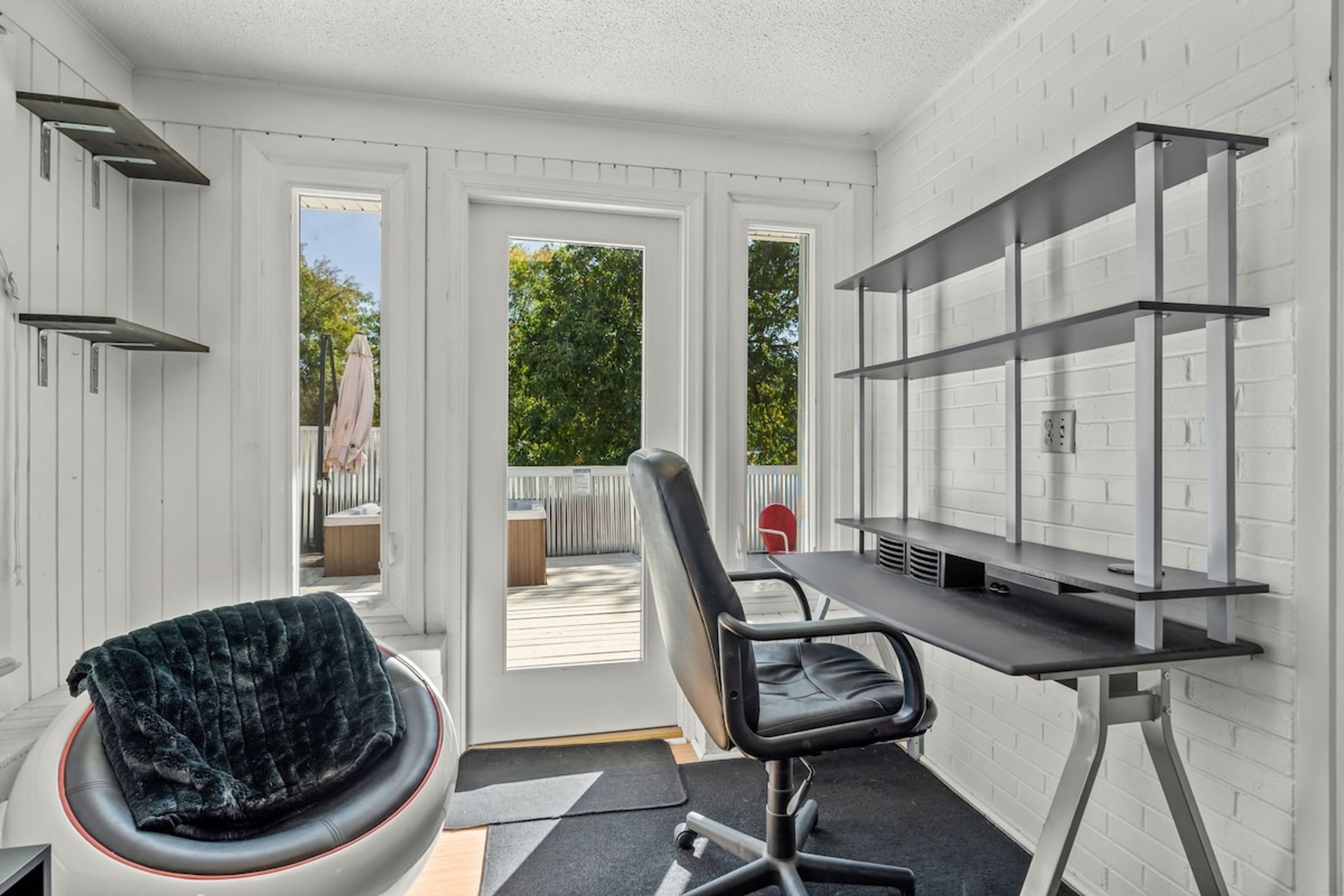Une chambre moderne équipée d’un bureau, d’une chaise et d’un coin salon confortable avec une couverture.