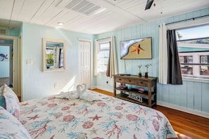 A bedroom with a bed, a dresser, a mirror, and a window with a view. - Beach Life 3 - Sunshine Lane (Treasure Island)