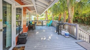 A covered outdoor area with a wooden deck, a grill, and a welcome mat. - Beach Life 3 - Sunshine Lane (Treasure Island)