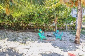 An outdoor seating area with chairs and a table, surrounded by trees and a palm tree. - Beach Life 3 - Sunshine Lane (Treasure Island)