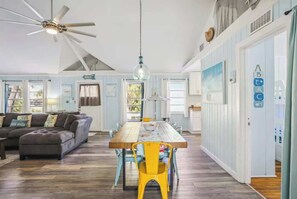 A spacious living room with a wooden dining table, a sofa, and a ceiling fan. - Beach Life 3 - Sunshine Lane (Treasure Island)