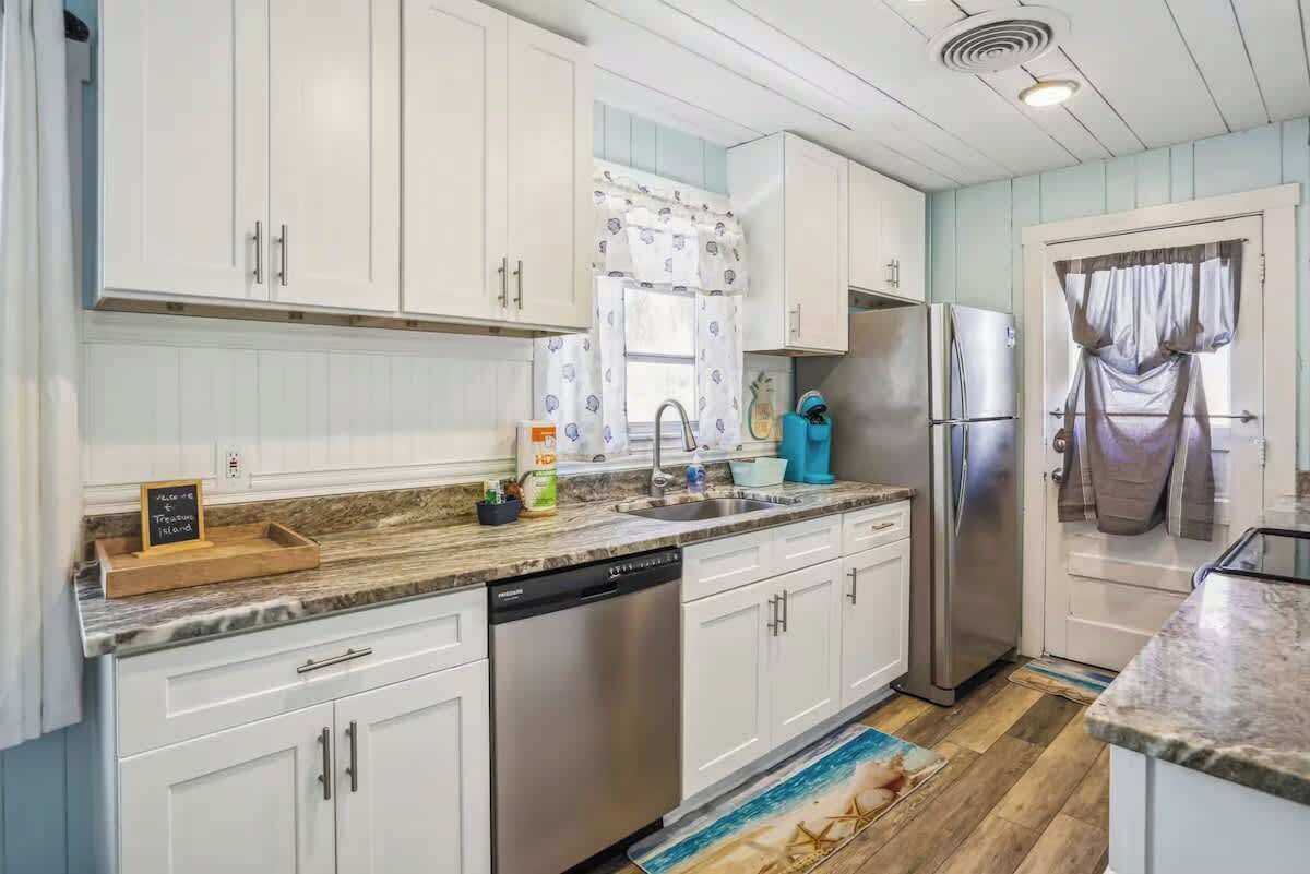 A kitchen with white cabinets, a stainless steel refrigerator, and a dishwasher.
